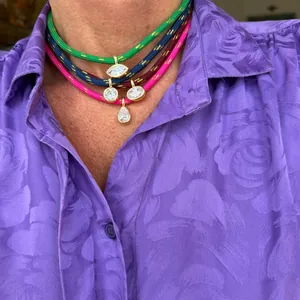 Detailed macro view of colorful cord chokers featuring various zircon pendants on model