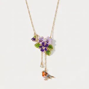 Dettaglio collana vintage in smalto con fiori viola e pettirosso