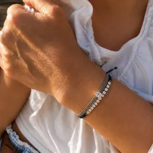 Detailaufnahme eines gewebten verstellbaren Armbands mit Tropfen- und Rundzirkonia am Handgelenk