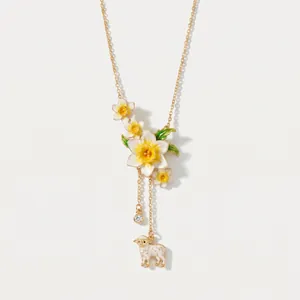 Dettaglio di una collana vintage con ciondolo a forma di narciso e pecora in smalto