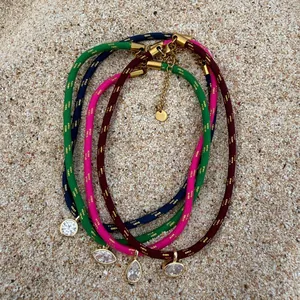 Detail view of colorful gold wire woven chokers with various zircon pendants