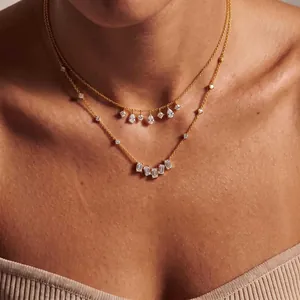 Elegant gold-plated double-layer necklace with pear and emerald cut zirconia accents.