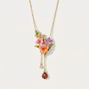 Dettaglio di una collana vintage in smalto con fiori colorati e nappa a coccinella