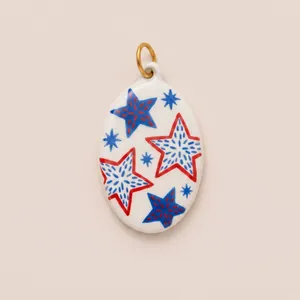 Detail of hand-painted enamel oval pendant featuring vibrant red and blue star patterns