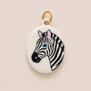 Detail view of hand-painted enamel zebra pendant with gold ring in a white oval ceramic style