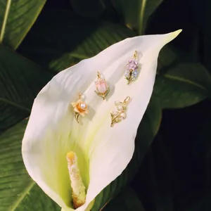 Detailed view of vintage enamel floral pendants with pearl on white calla lily