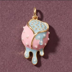 Primo piano di un ciondolo in smalto rosa e blu con piccoli dettagli in perle bianche