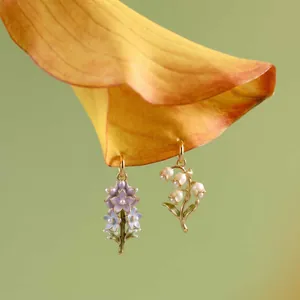 Macro detail of vintage enamel floral pendants featuring pearls and lily of the valley.