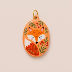 Macro view of a hand-painted enamel fox pendant featuring vibrant botanical patterns