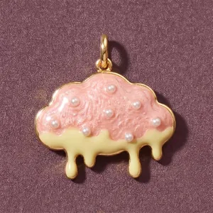 Dettaglio macro di un ciondolo a nuvola con smalto rosa strutturato e piccole perle