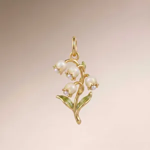 Close-up of elegant gold lily of the valley pendant featuring enamel and pearls