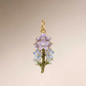 Detail showing fine enamel work and pearl accents on the vintage gold flower pendant.