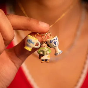 Detailed view of 3D hand-painted ceramic charms including a girl and tiny cups.
