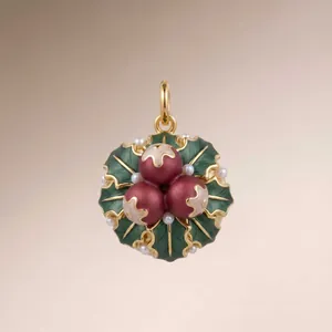 Detail of a 3D holly pendant with green enamel leaves, red berries, and delicate pearls.