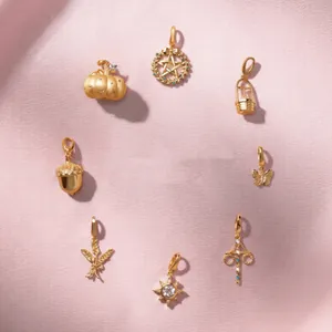 Detailed view of vintage gold-plated charms with zircon inlays on pink silk background
