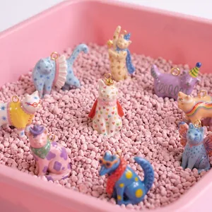 Dettaglio di vari ciondoli a forma di gatto fantasy dipinti a mano in un vassoio rosa