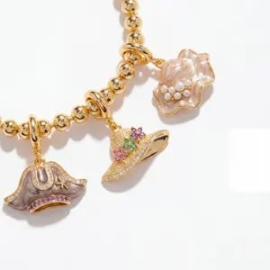 Detailed macro view of vintage enamel hat pendants on a luxury gold beaded jewelry bracelet