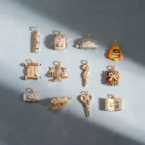 Collection of twelve stationery-themed enamel and pearl pendants shown in detail