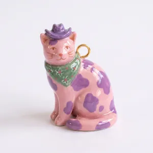 Vista dettagliata del ciondolo a forma di gatto rosa dipinto a mano con cappello cowboy