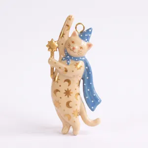 Primo piano di un ciondolo a forma di gatto in ceramica dipinto a mano con motivi celesti.