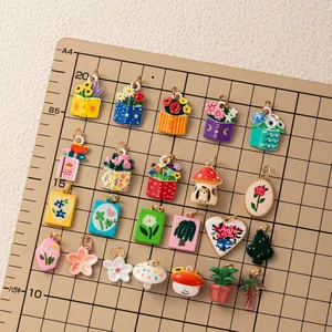 A collection of colorful 18K gold plated charms with flower and cat motifs on a grid mat