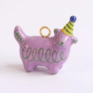 Dettaglio di un ciondolo a forma di gatto in ceramica viola dipinto a mano con spirali