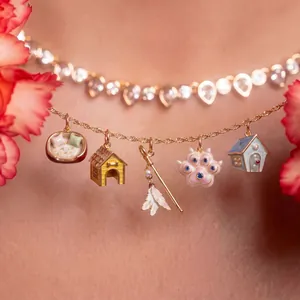 Detailansicht einer goldenen Kette mit Tier-Anhängern, Emaille und kleinen Zuchtperlen.