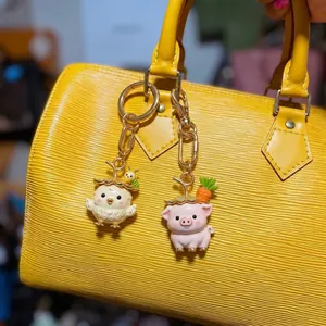Detail of cute pig and chick animal bag charms hanging from a yellow leather bag