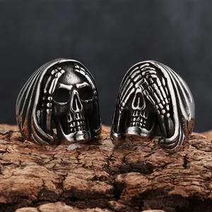 Close-up view of vintage gothic skull rings for men featuring skeletal hand details on wood