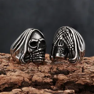 Detailed view of vintage silver-tone skull rings with reaper designs on a wood bark surface