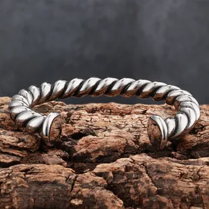 Vintage twisted titanium steel cuff bracelet for men on a textured wood background