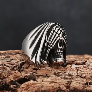 Macro detail of retro reaper skull titanium steel ring with skeleton hands design