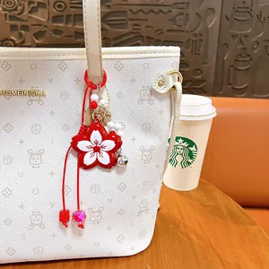 Exquisite red and white cherry blossom flower keychain charm hanging on a patterned tote bag