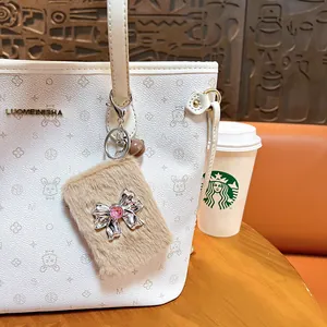 Plush bow keychain with foldable makeup mirror hanging on a white handbag