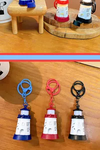 Detailed view of three lighthouse light-up keychains in blue, red, and black colors.