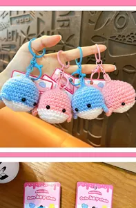 Detailed macro view of handmade crochet whale keychains in pink and blue colors
