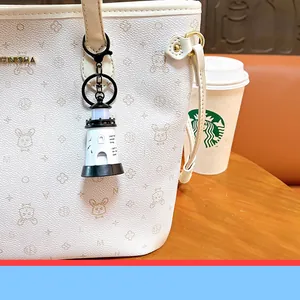 Detail view of a creative glowing lighthouse keychain hanging on a white patterned tote bag