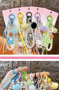 Vista detallada de dijes para bolsos de perlas con pompones coloridos y mini bolsos.