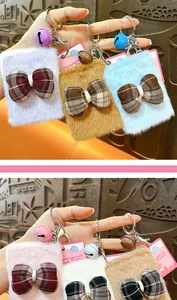Detailed view of colorful plush bow mirror keychains with small bells in various pastel colors.