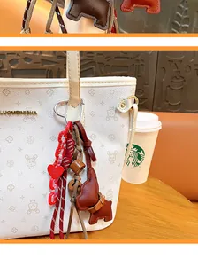 Close-up detail of a vintage leather puppy keychain charm attached to a white tote bag