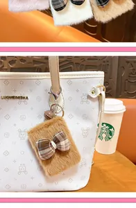 Close-up of a brown plush bow-knot mirror keychain charm attached to a white tote bag