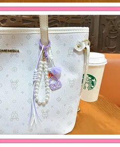 Detalle de un colgante para bolso de perlas moradas con pompón y mini bolso floral
