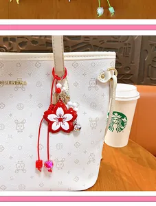 Detail view of a cute red and white cherry blossom bag charm on a stylish white tote.