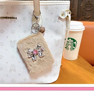 Detailed macro view of a fluffy plush bow folding mirror keychain charm on a white handbag