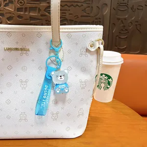 Cute frosted blue bear keychain bag charm with motivational strap hanging on a white tote
