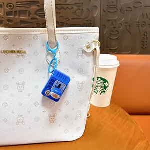 Porte-clés levier de vitesse miniature bleu avec fonction vocale accroché à un sac blanc élégant.
