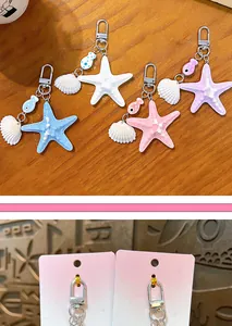 Nahaufnahme von farbenfrohen Seestern- und Muschel-Anhängern auf rosa Displaykarten.