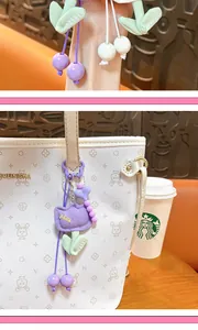 Detail view of a purple plush tulip bag charm with 'nice' embroidery on a white bag.