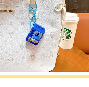 Gros plan d'un porte-clés levier de vitesse bleu accroché à un sac à main blanc.