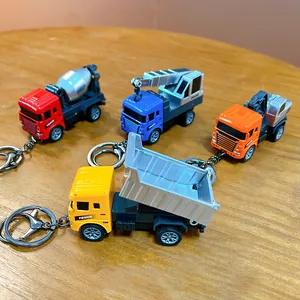 Set di quattro portachiavi a forma di camion da cantiere in lega su superficie di legno